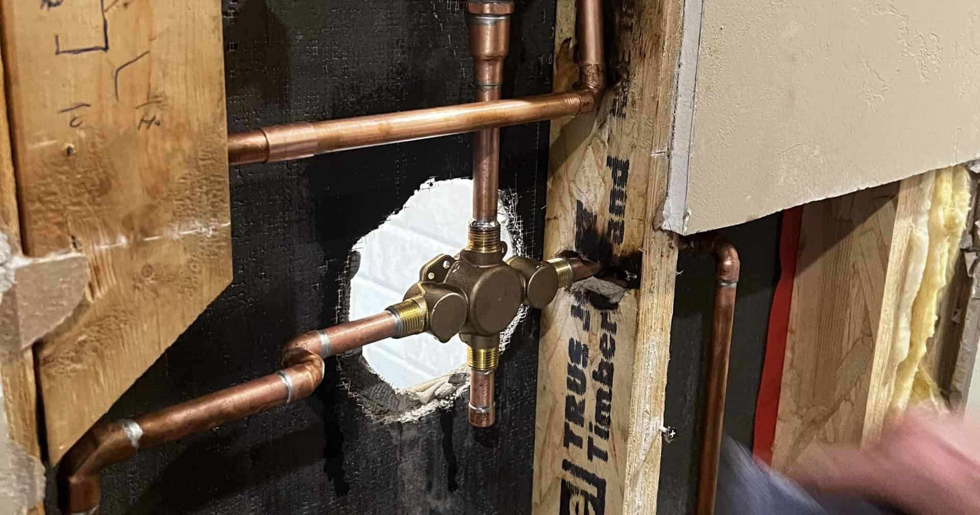 Copper pipes next to a black wall