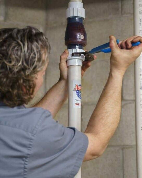man fixing a pipe that has Austin Company logo