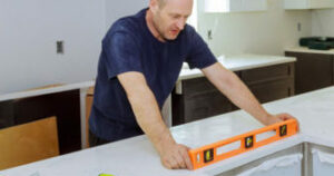 Man leveling with countertops of making a modern domestic kitchen cabinets